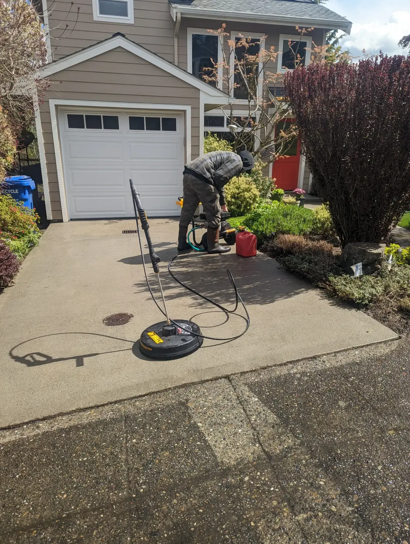 Pressure washing driveway in front of garage, second worker behind