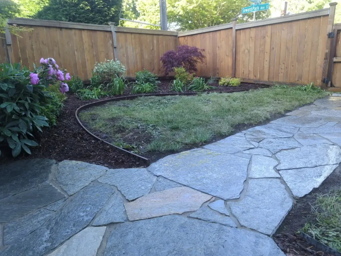Wide flagstone terrace meeting lawn and peony-filled planting border