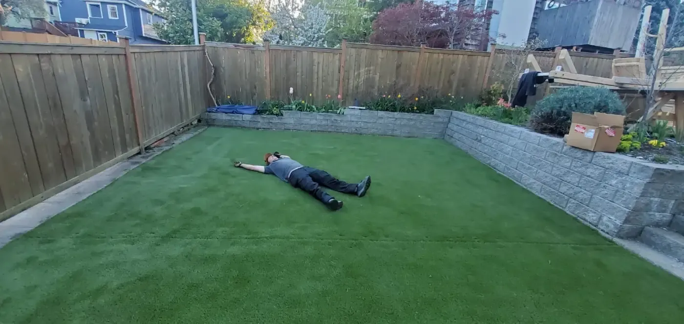 Artificial turf yard bordered by grey block wall and wood fence