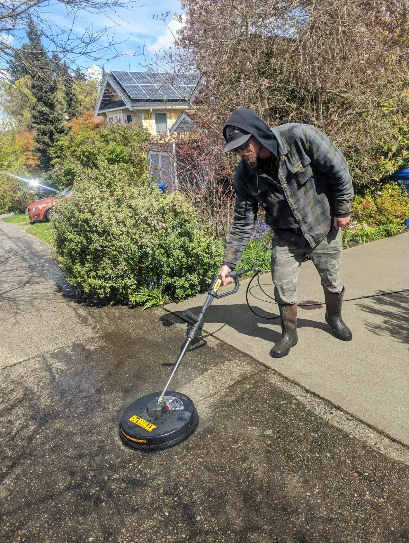 Crew member pressure washing sidewalk with rotary surface cleaner