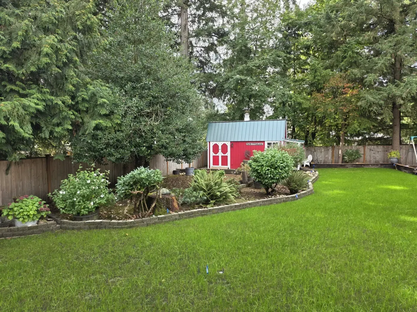 Green backyard lawn edged by stone border and shade bed