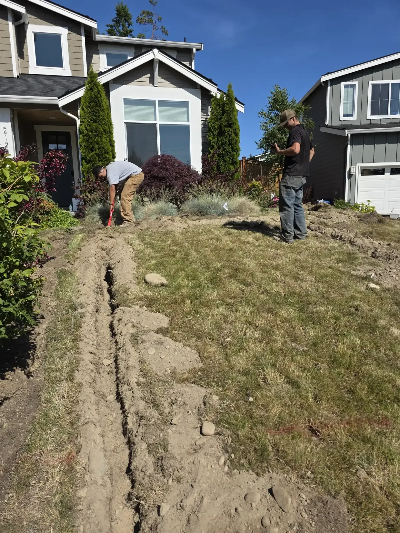Crew digging trench line across front lawn at new home