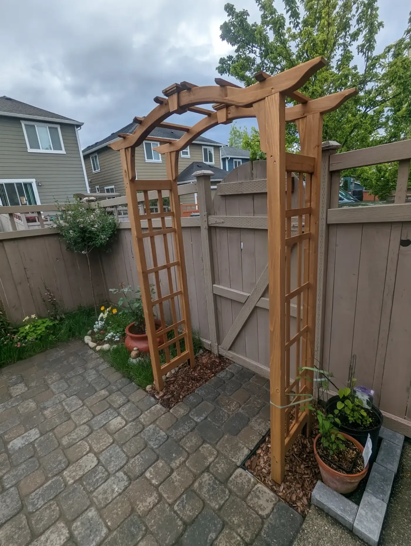 New cedar arbor with trellis sides on small paver courtyard