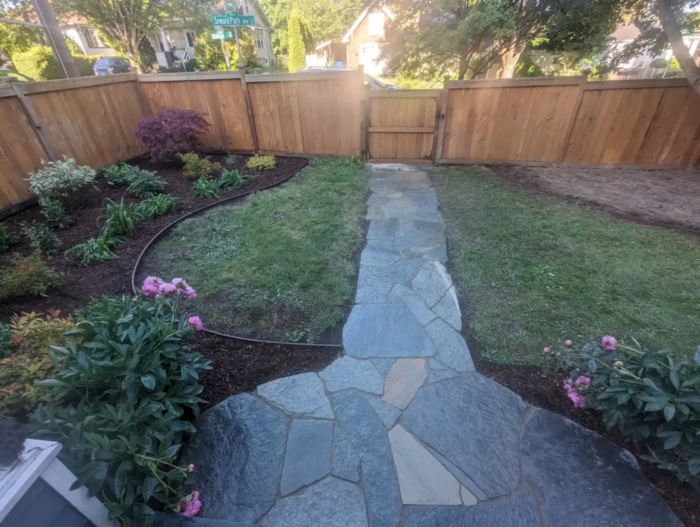 Flagstone walkway crossing lawn toward cedar gate and fence