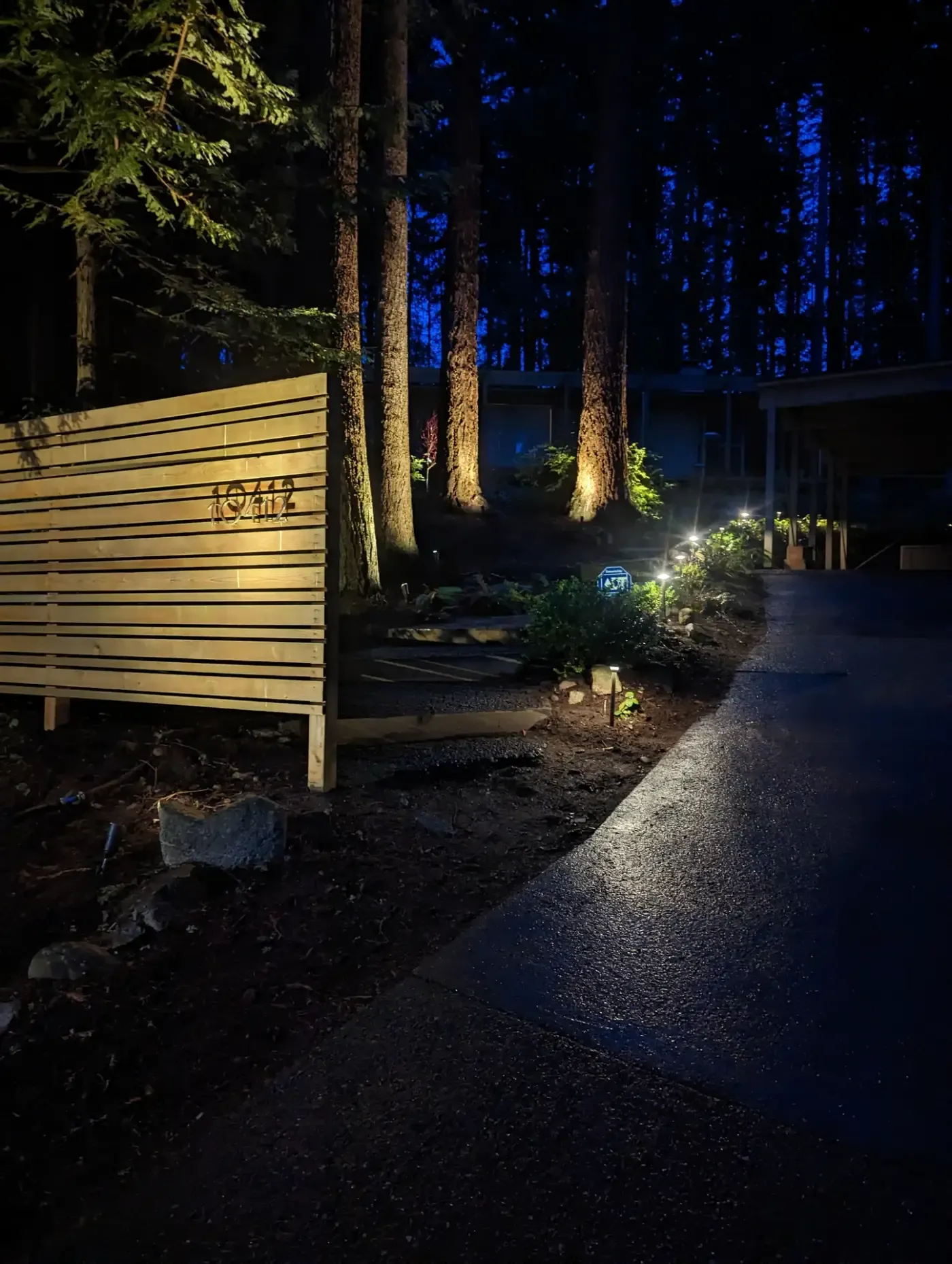 Night view of illuminated slat screen and path lights by driveway