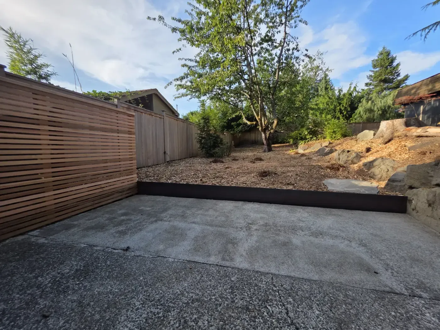 Cedar slat screen and fence enclosing new concrete pad