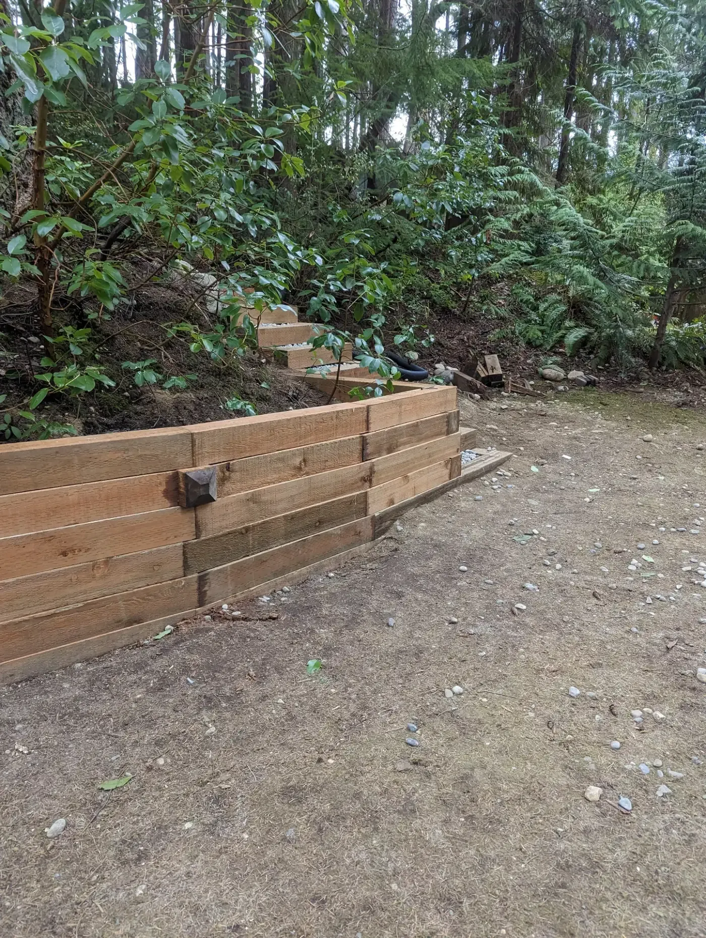 Close view of cedar wall tiers holding back forested slope