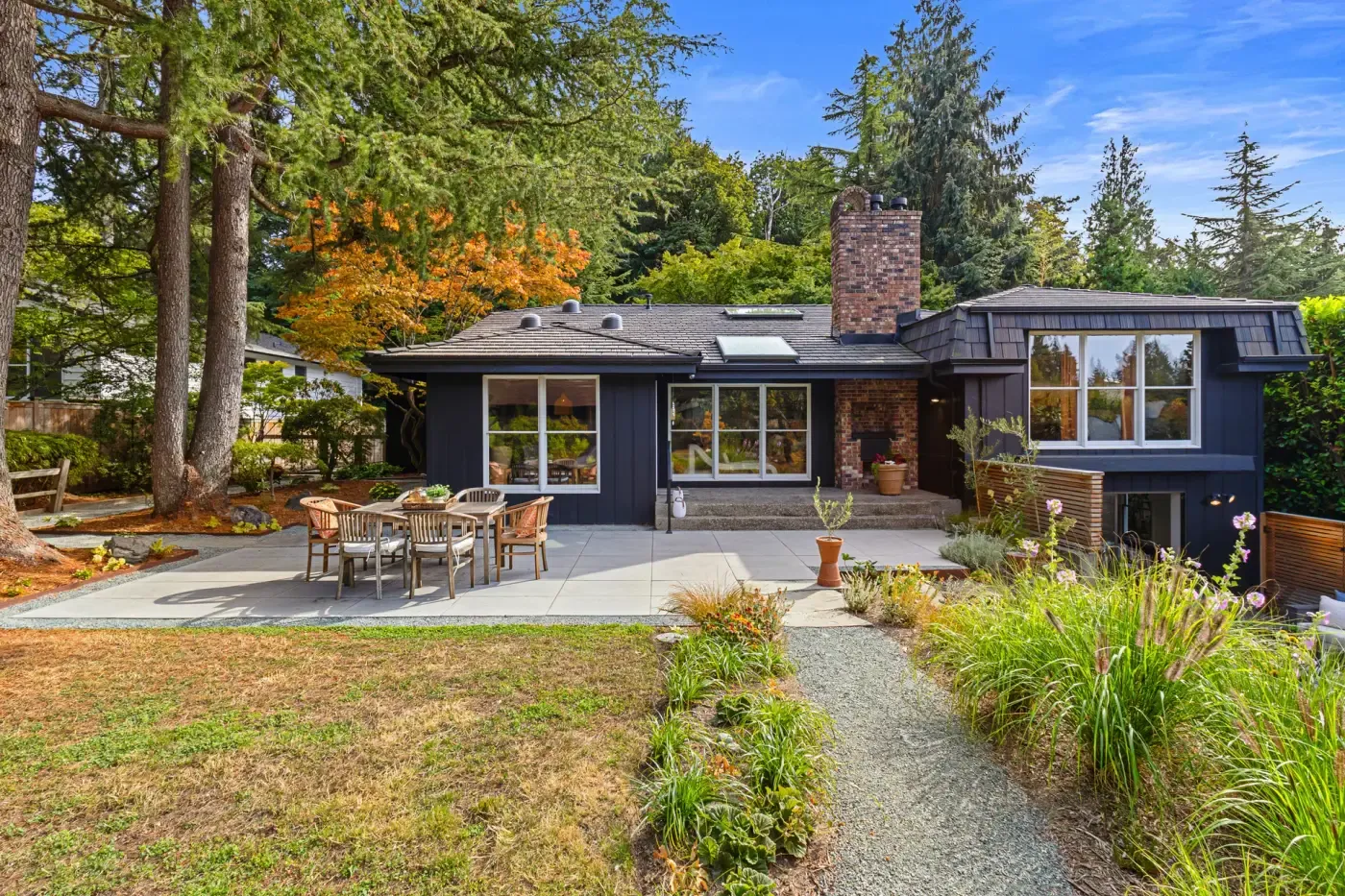Whole backyard view: slab dining patio, gravel path through ornamental grasses and a Japanese maple in fall color