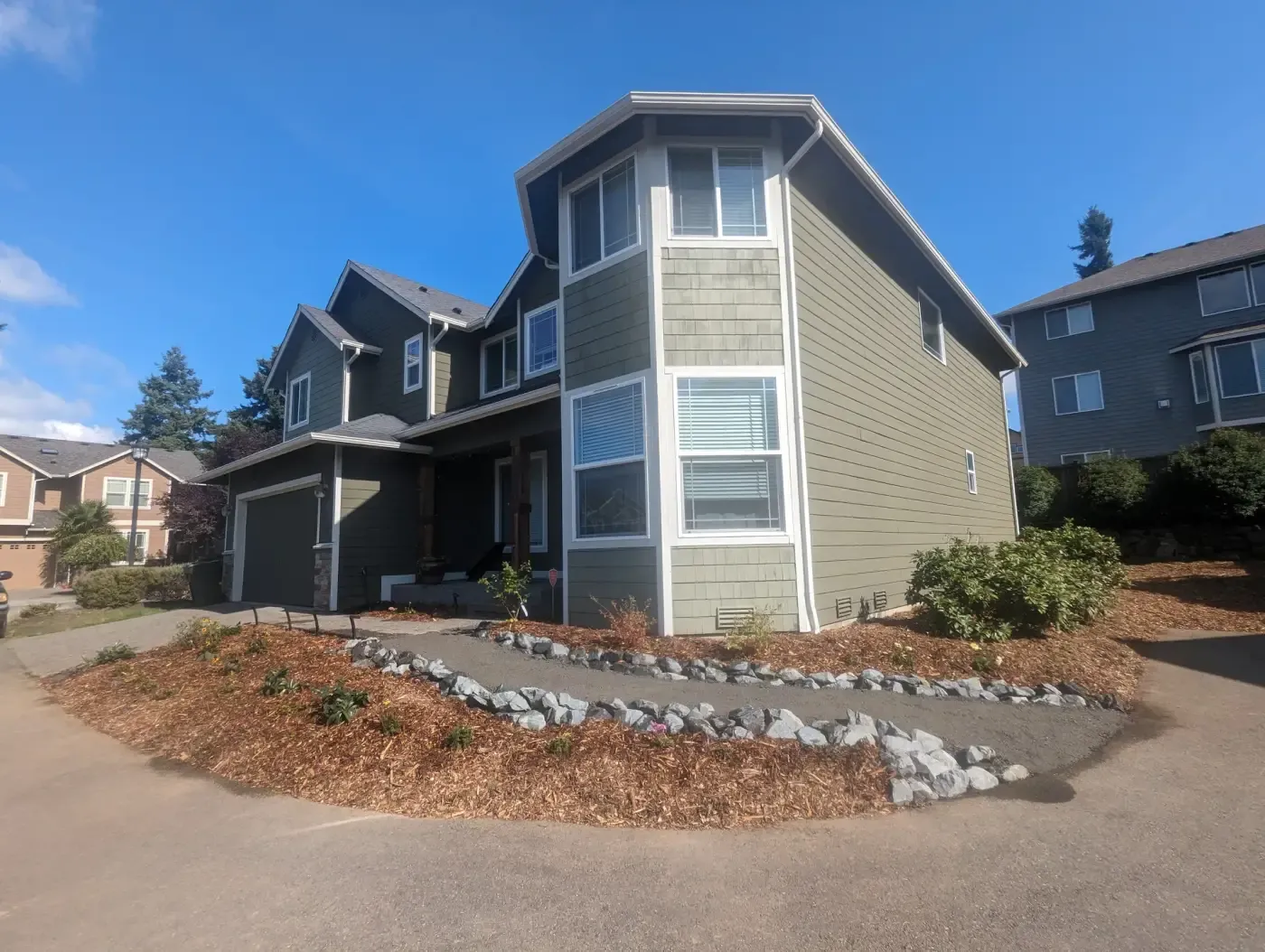 Front yard bark beds edged with white rock at two-story house