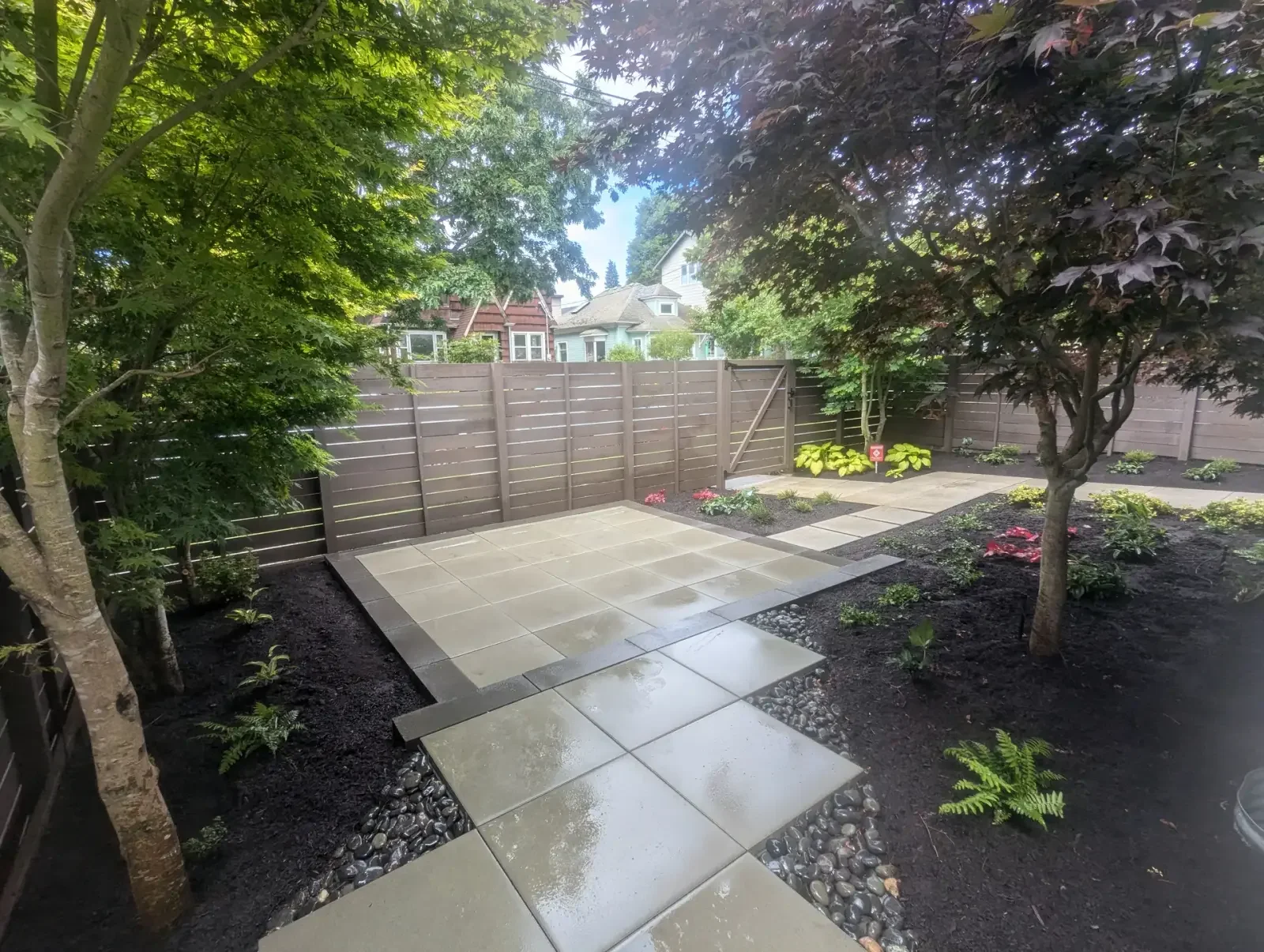 Courtyard of large concrete slabs with a river rock margin