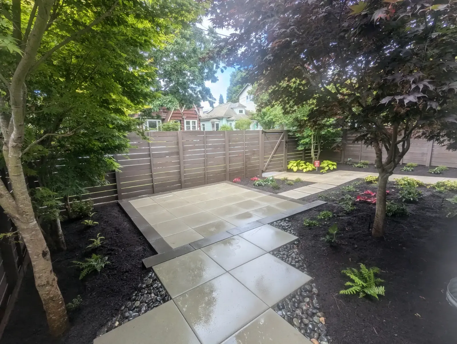 Courtyard of large concrete slabs with a river rock margin