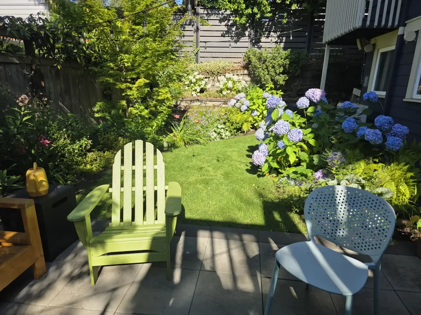 Hydrangeas in bloom, small lawn, chairs on stone terrace