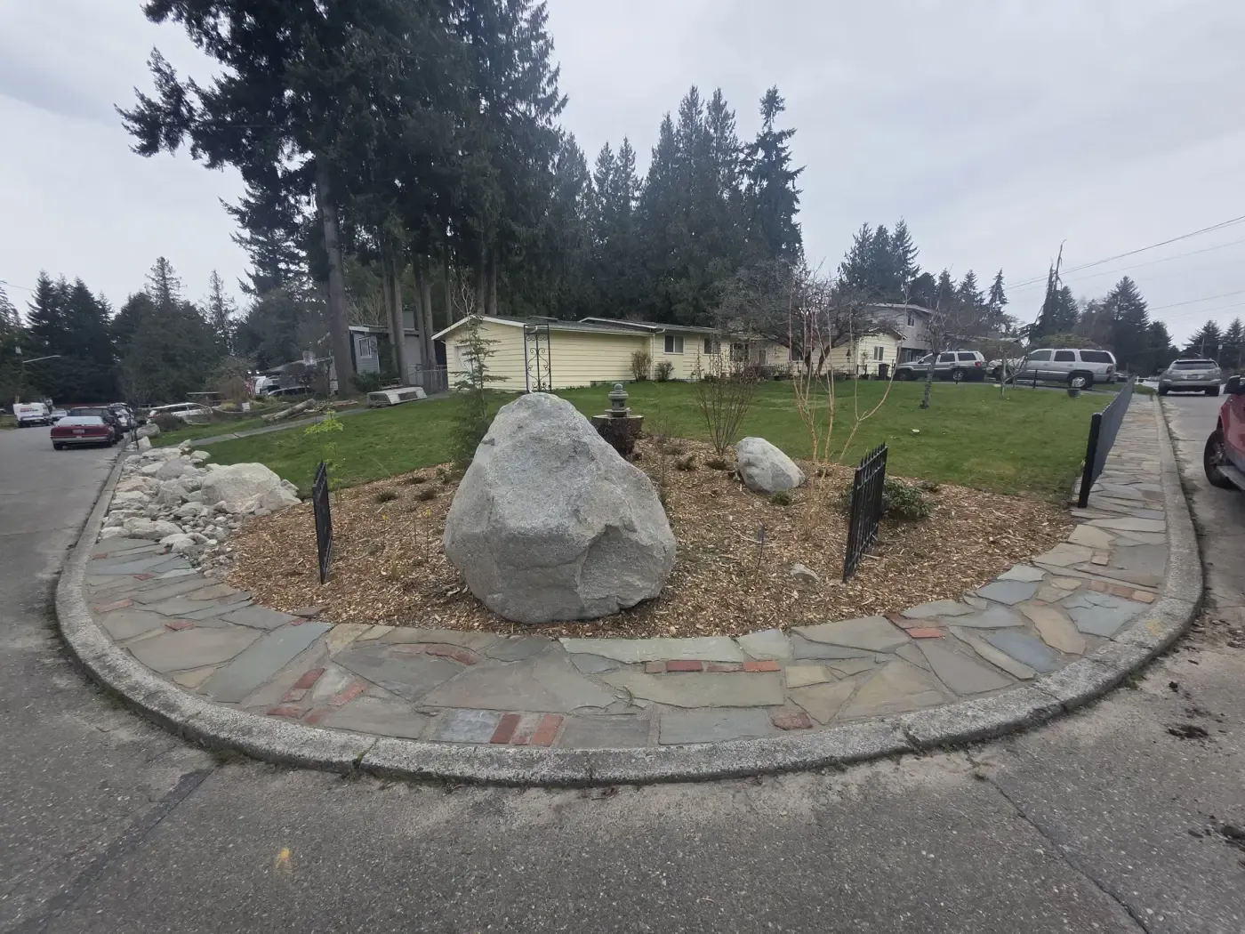 Large granite boulders in bark bed edged with flagstone apron