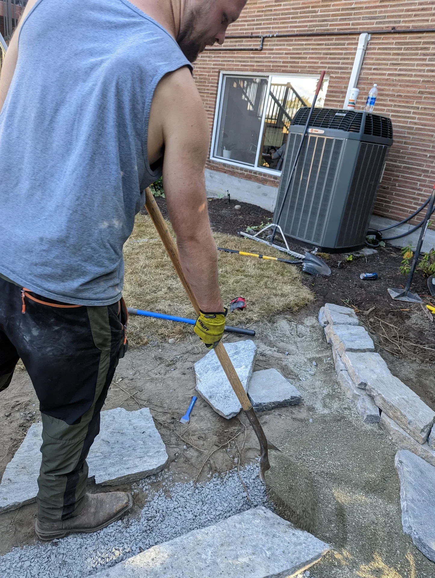 Worker raking a sand setting bed ready for flagstone