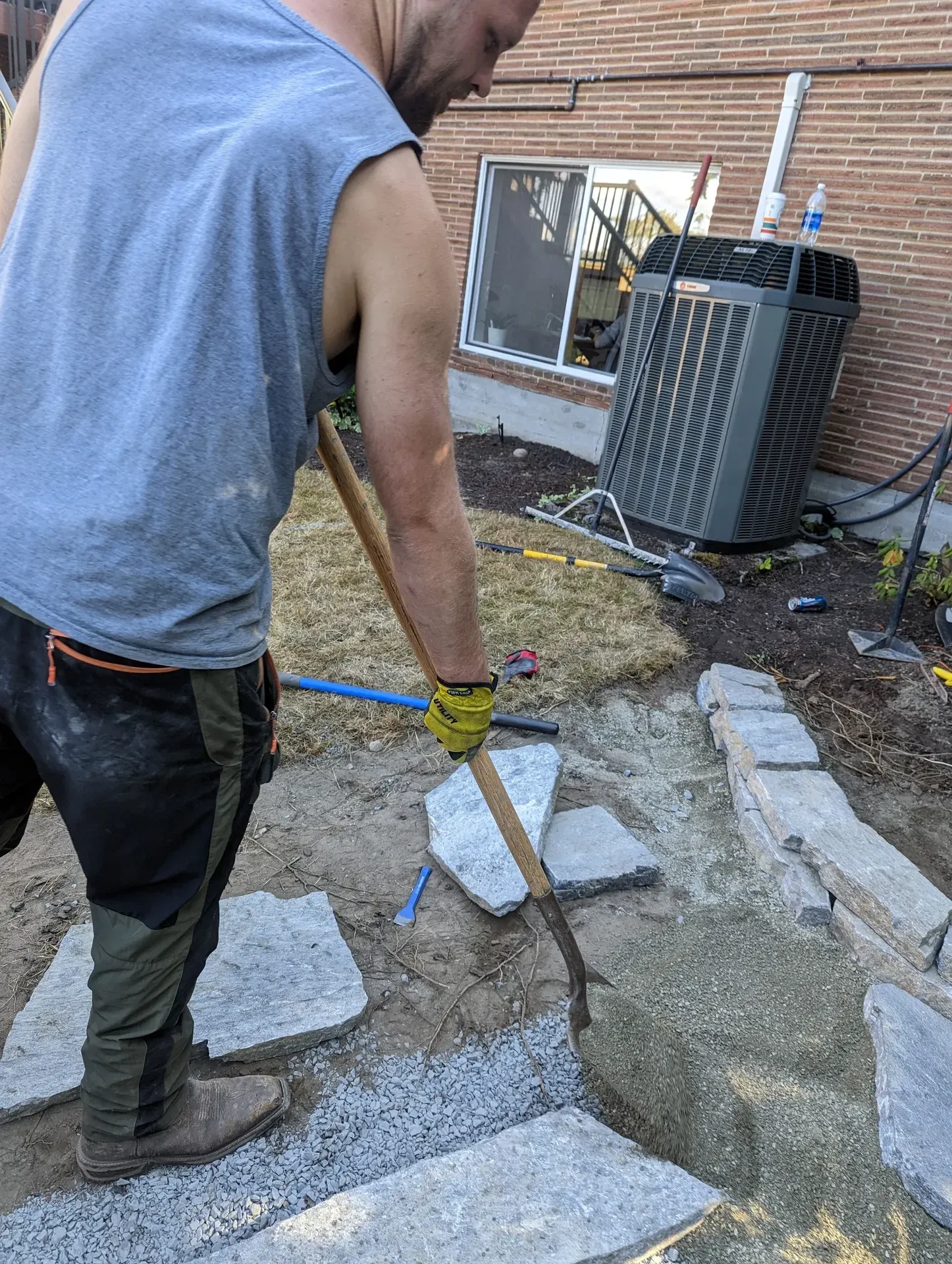 Worker raking a sand setting bed ready for flagstone