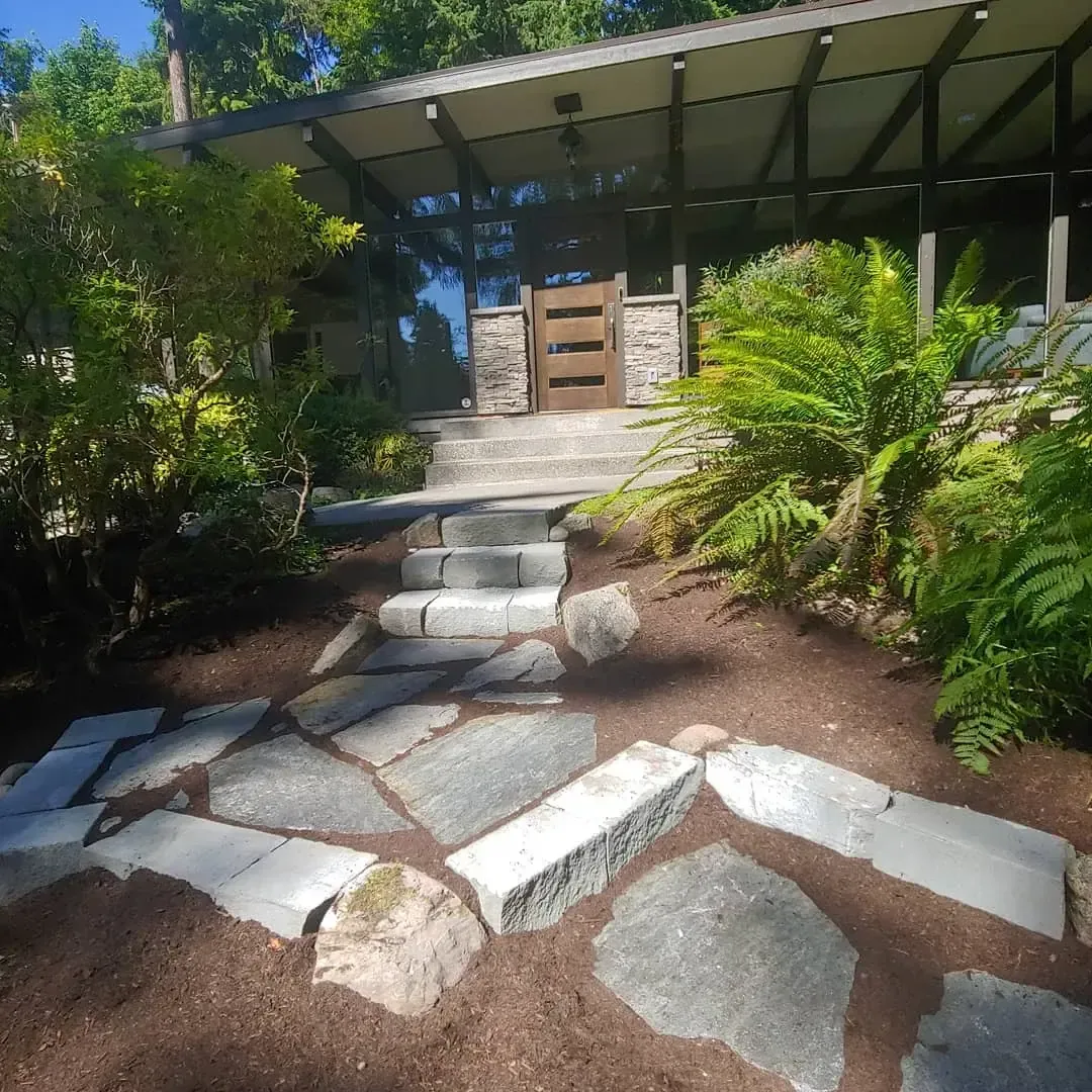 Flagstone landing and stone treads approaching mid-century glass entry