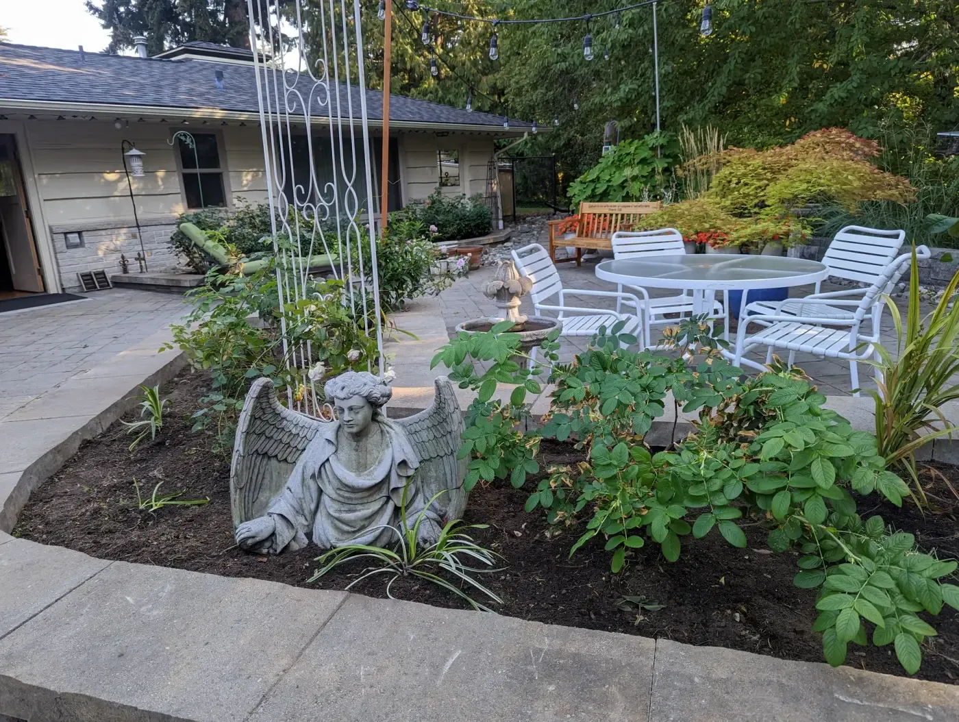Patio dining set and fire bowl beside statue in raised bed
