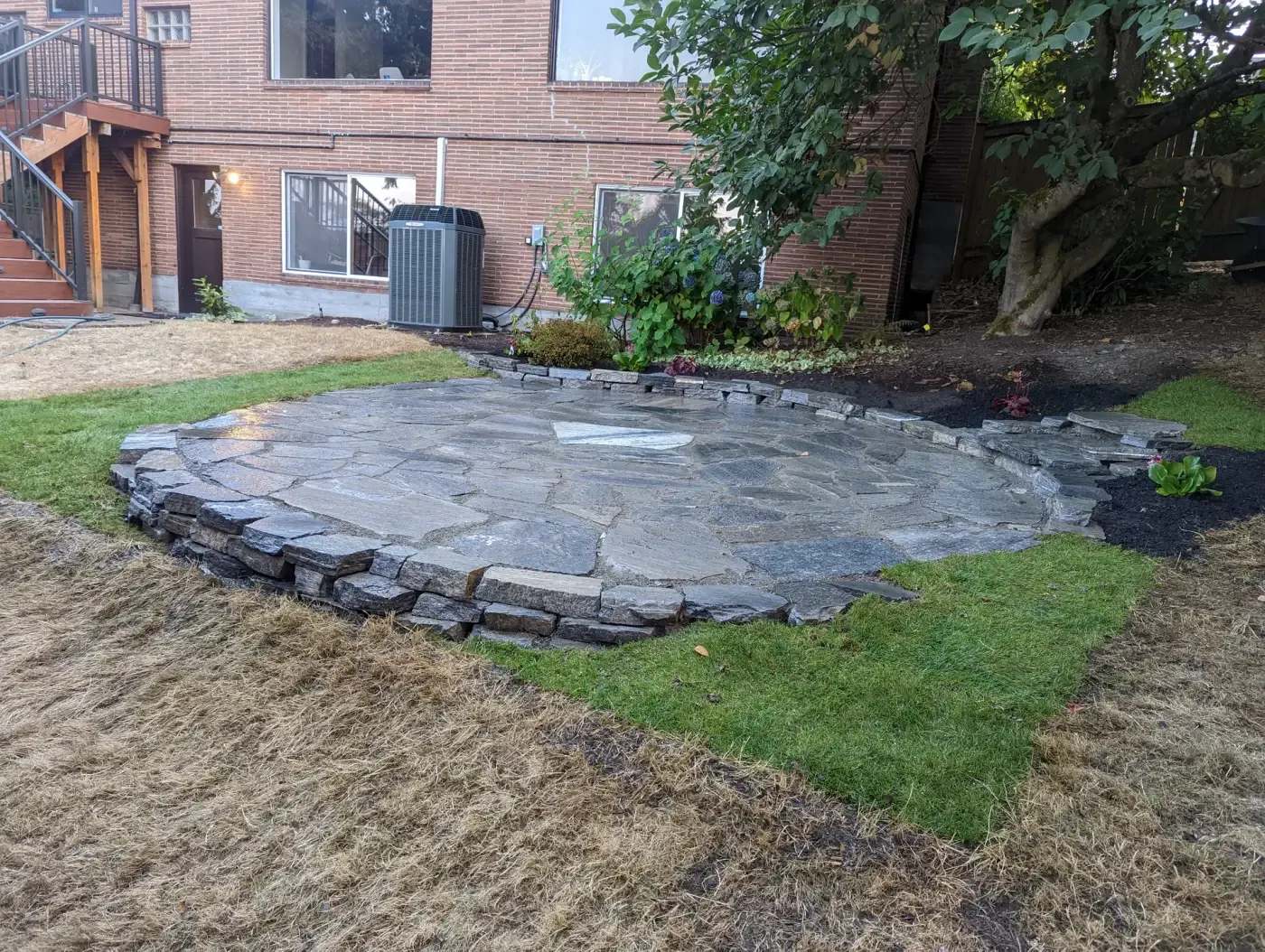 Completed flagstone patio with stacked edge, lawn and new beds