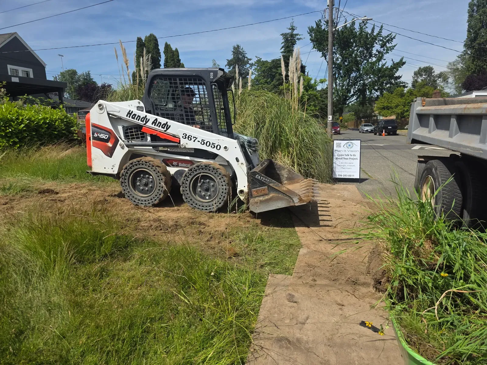 Compact track loader and dump truck at the curb as the old lawn comes out