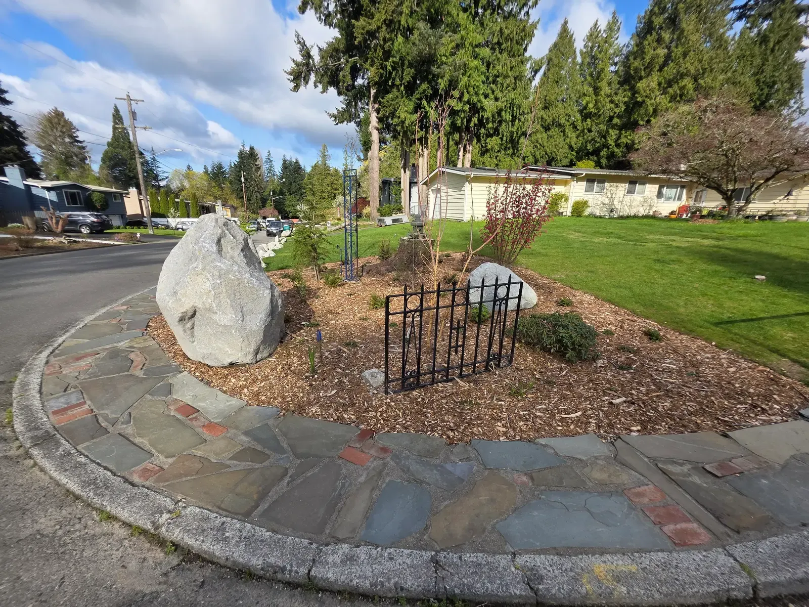 Wide view of the corner, boulder and flagstone path curving to the street