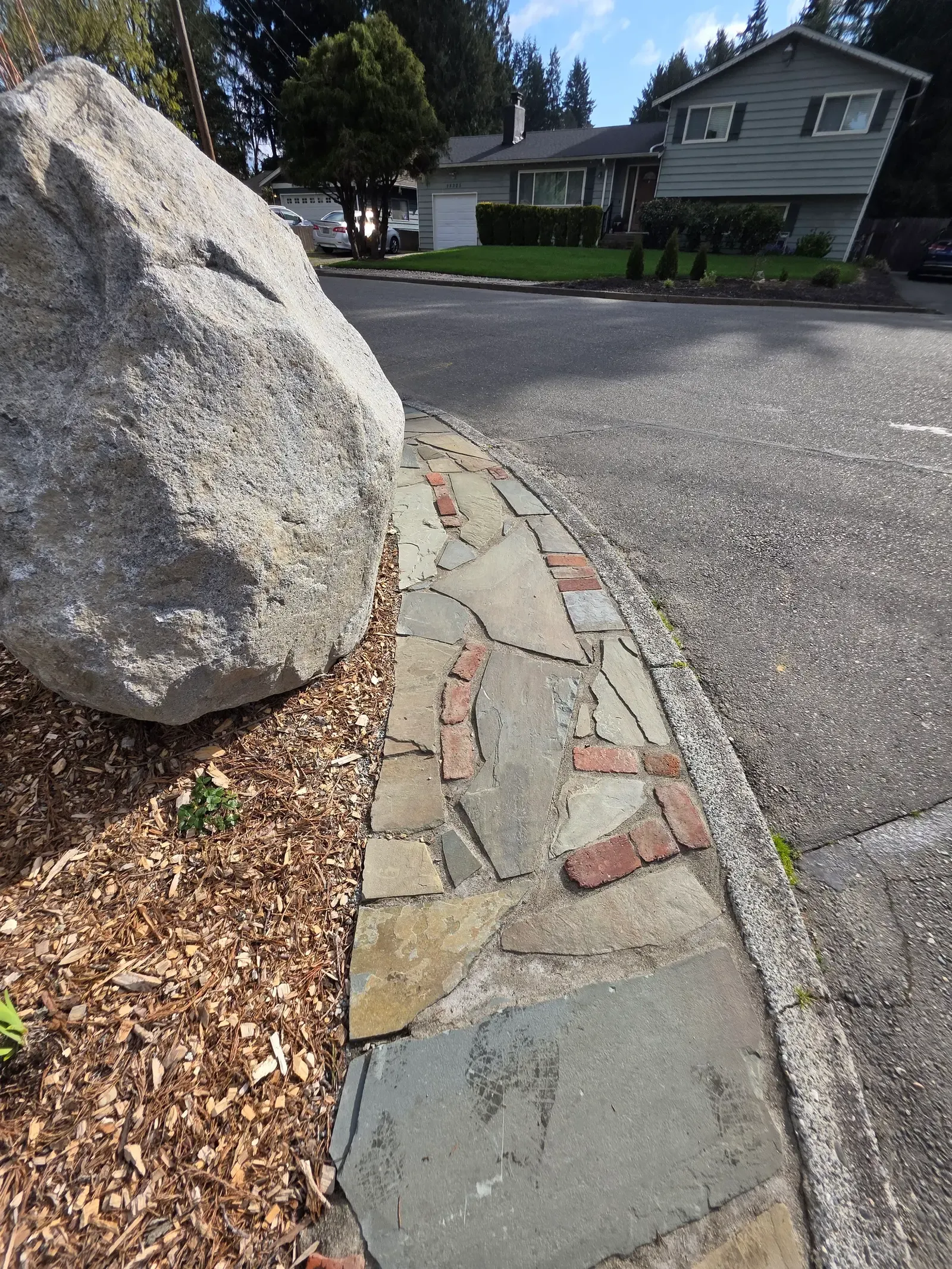 Detail of the boulder meeting the flagstone and brick path at the curb