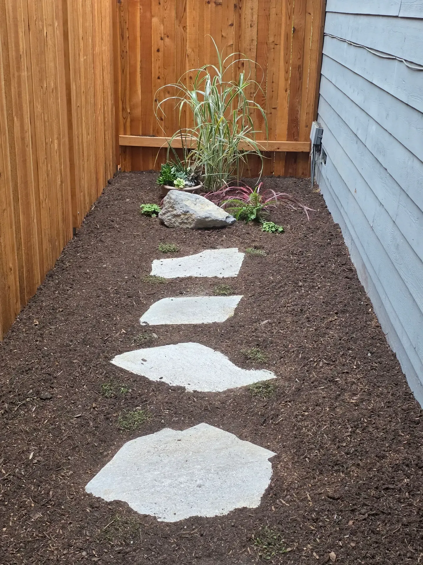 Flat natural stone steppers in fresh soil along the side yard passage