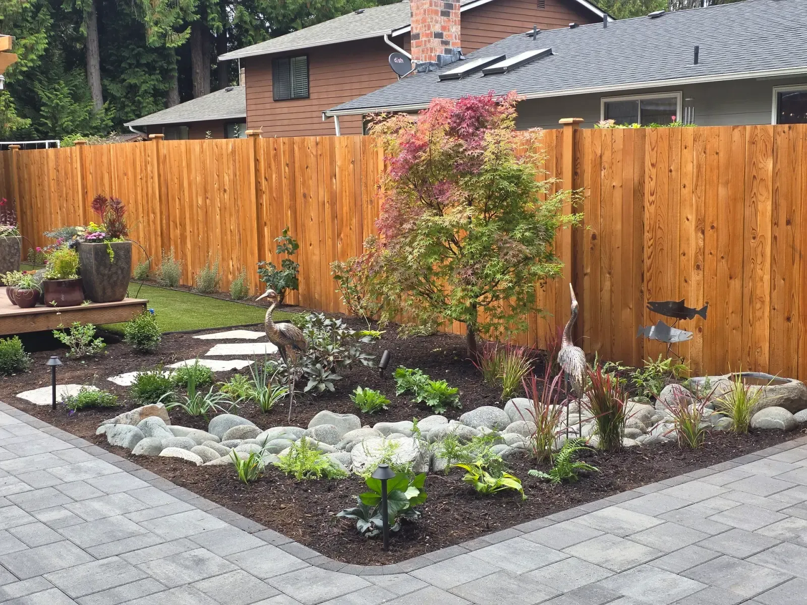 Planting bed wrapped by the paver path, with the river rock stream, steppers and a Japanese maple against the cedar fence