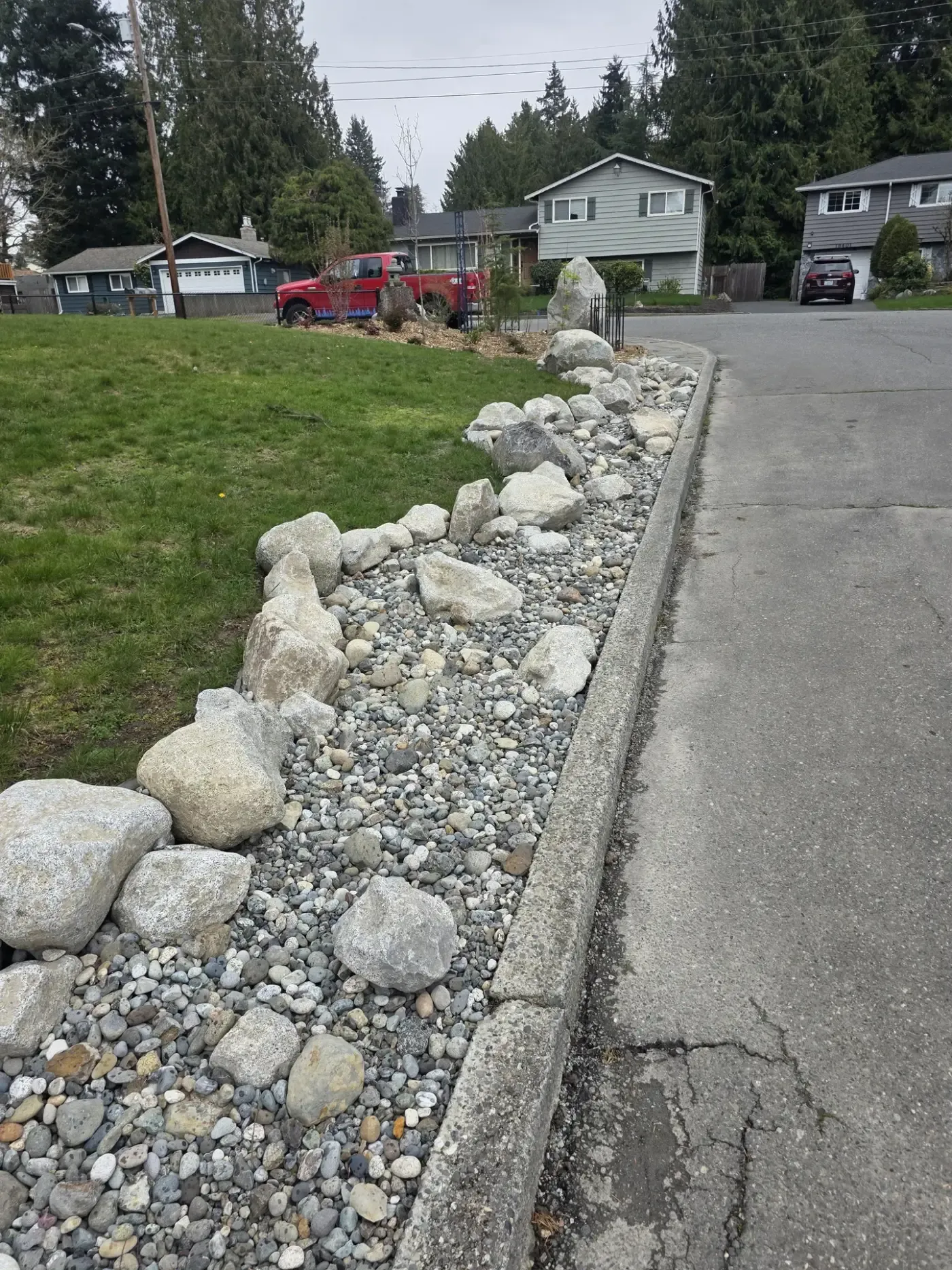Boulder and cobble verge separating lawn from street along curb