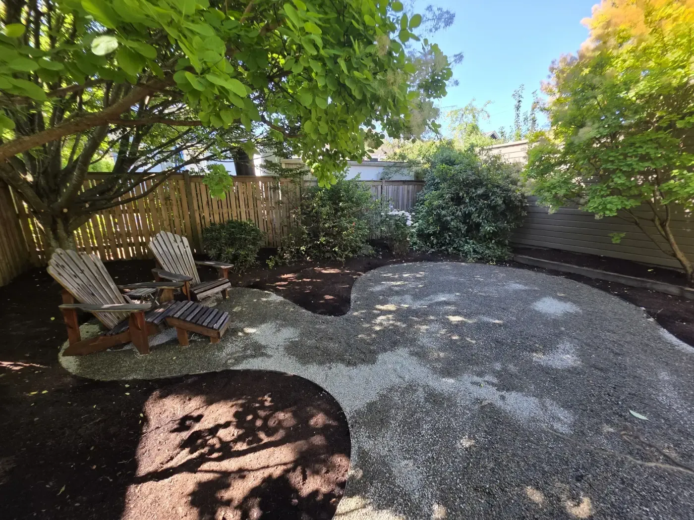 Crushed gravel seating area under trees with wood chairs