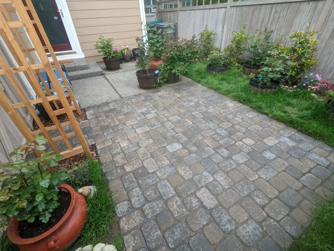 Grey cobble paver terrace beside back door and potted plants