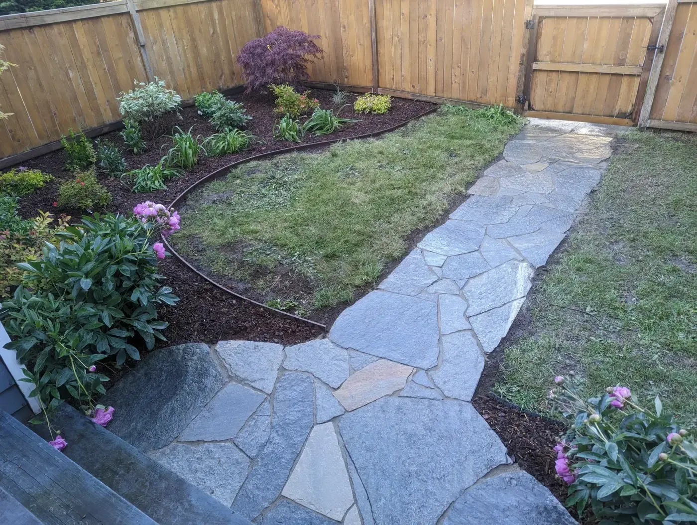 Irregular blue-grey flagstone path running between lawn and border