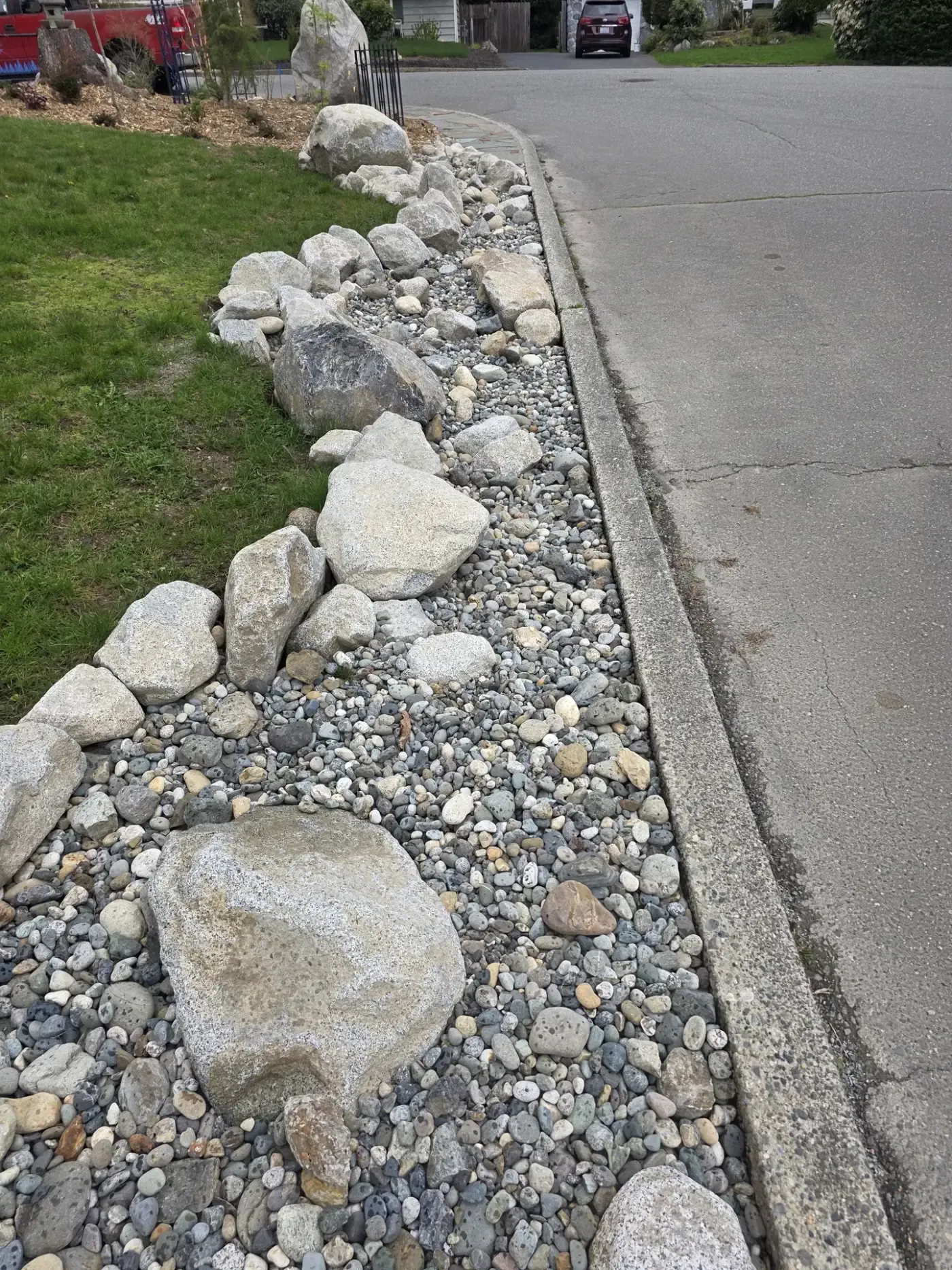 Closer view of cobble strip and set boulders beside concrete curb