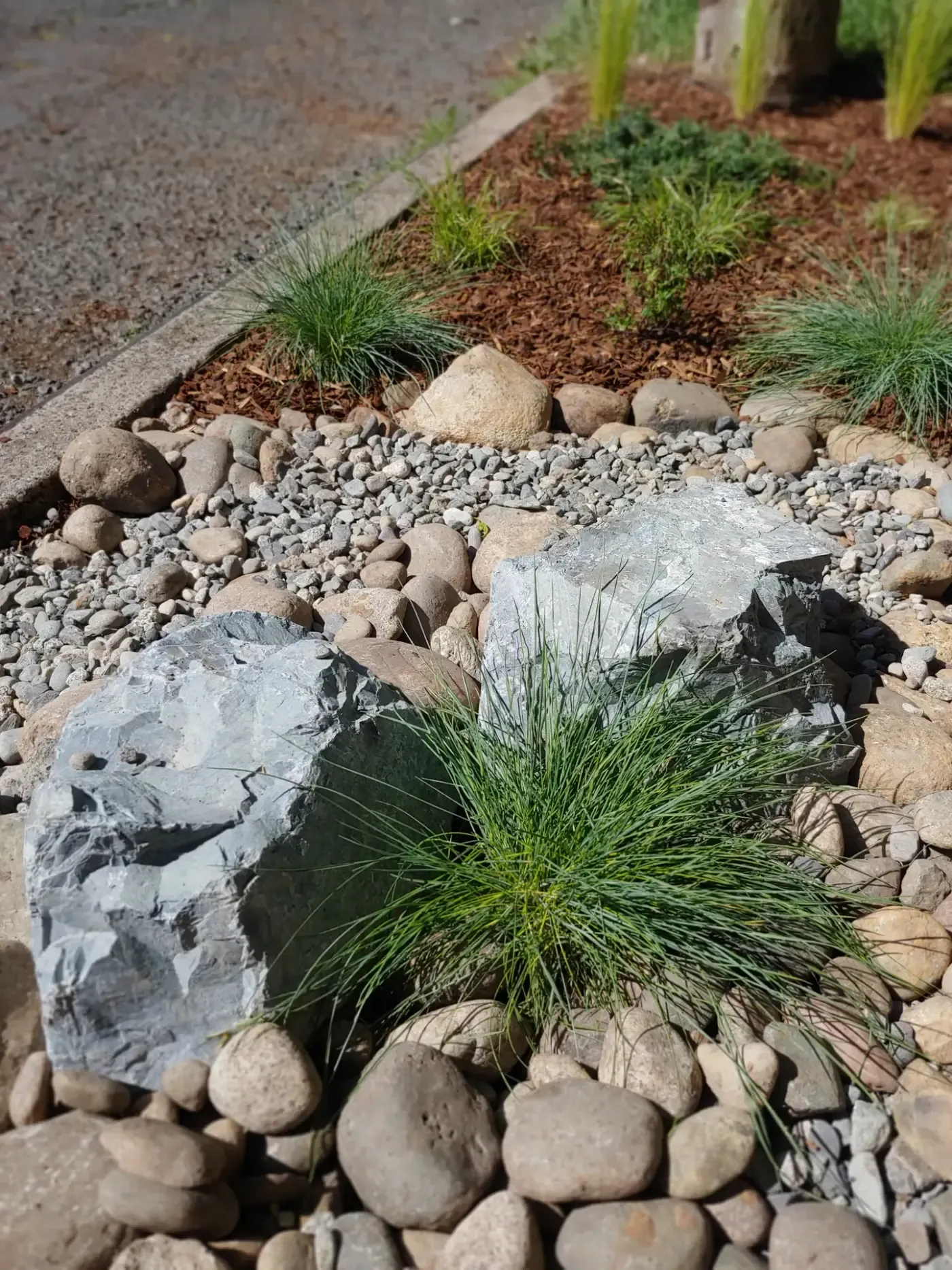 Grey slate accent boulders set in river rock with fescue