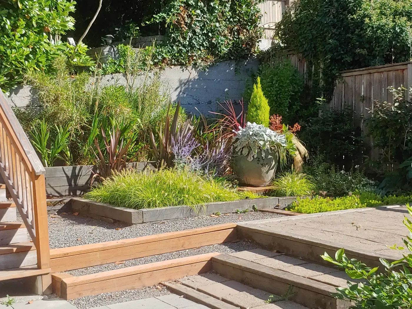 Wood stairs and landing beside gravel terrace and grass plantings