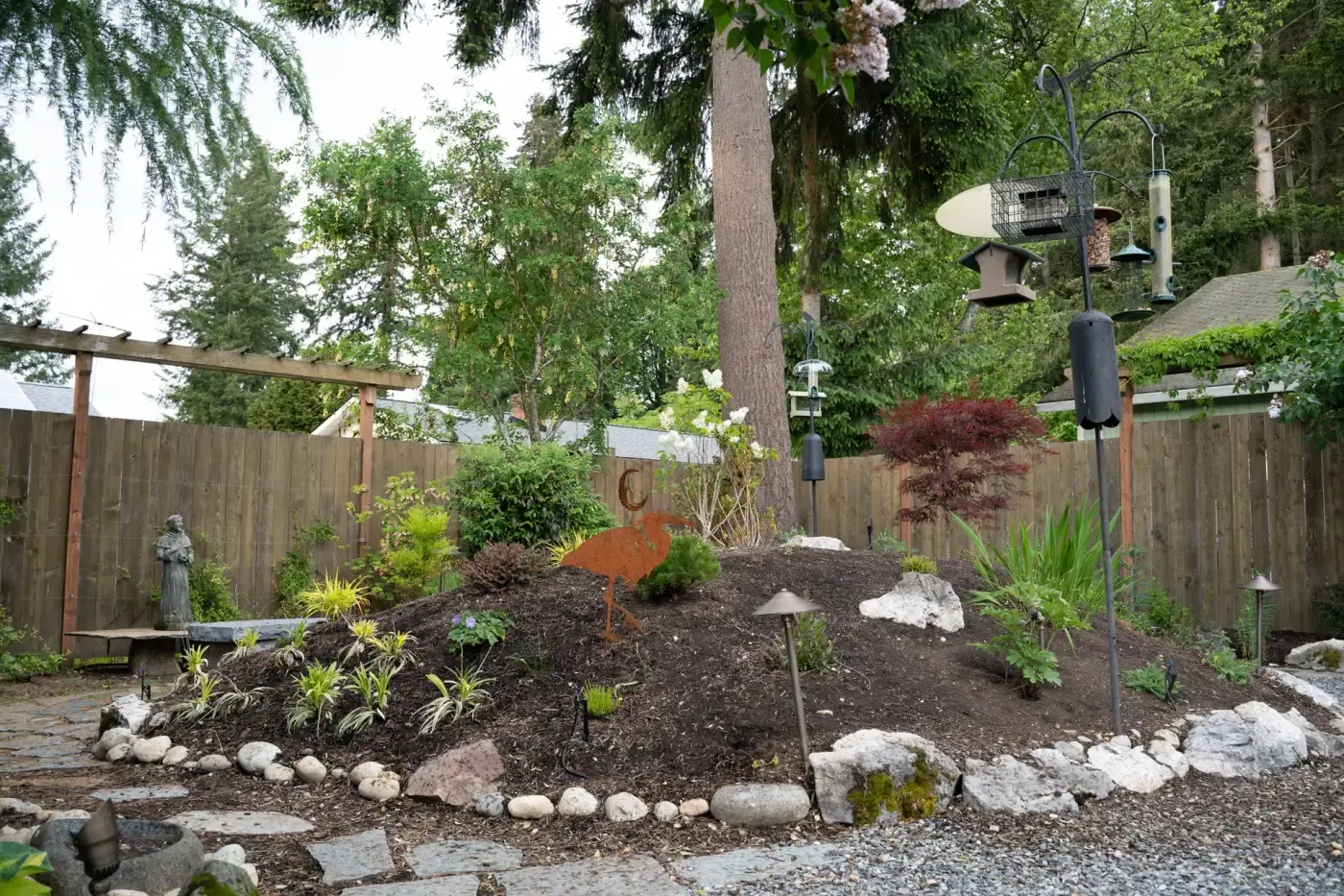 Pale boulders ring a planted mound with heron sculpture