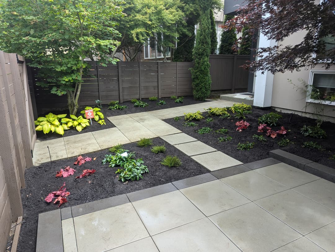 landscaped backyard with stone pathways, colorful flower beds, and lush greenery.