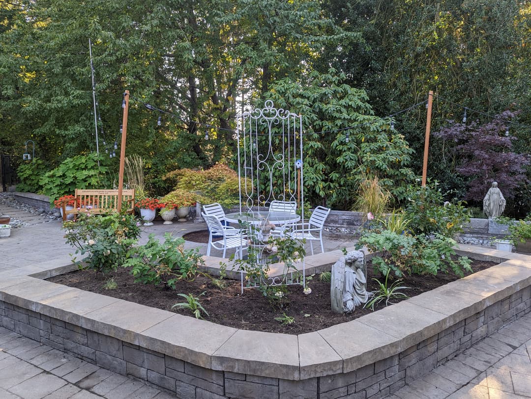 Colorful garden scene with seating area, decorative metal arch, and lush greenery.