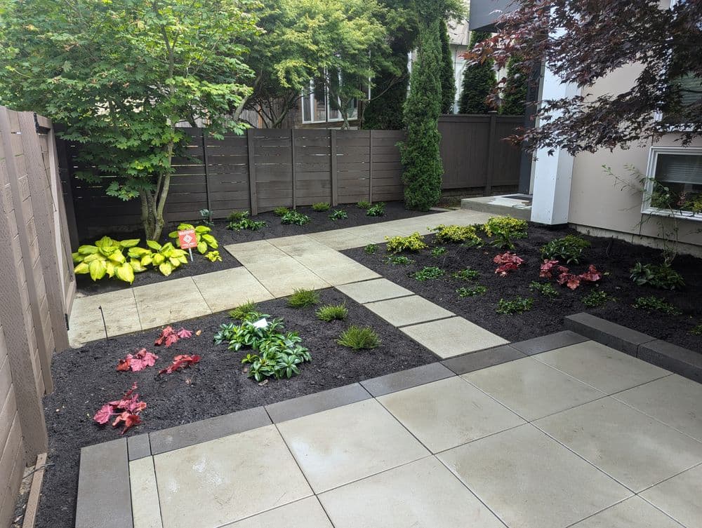 Lush garden with paved patio, colorful flowers, and well-maintained landscaping.